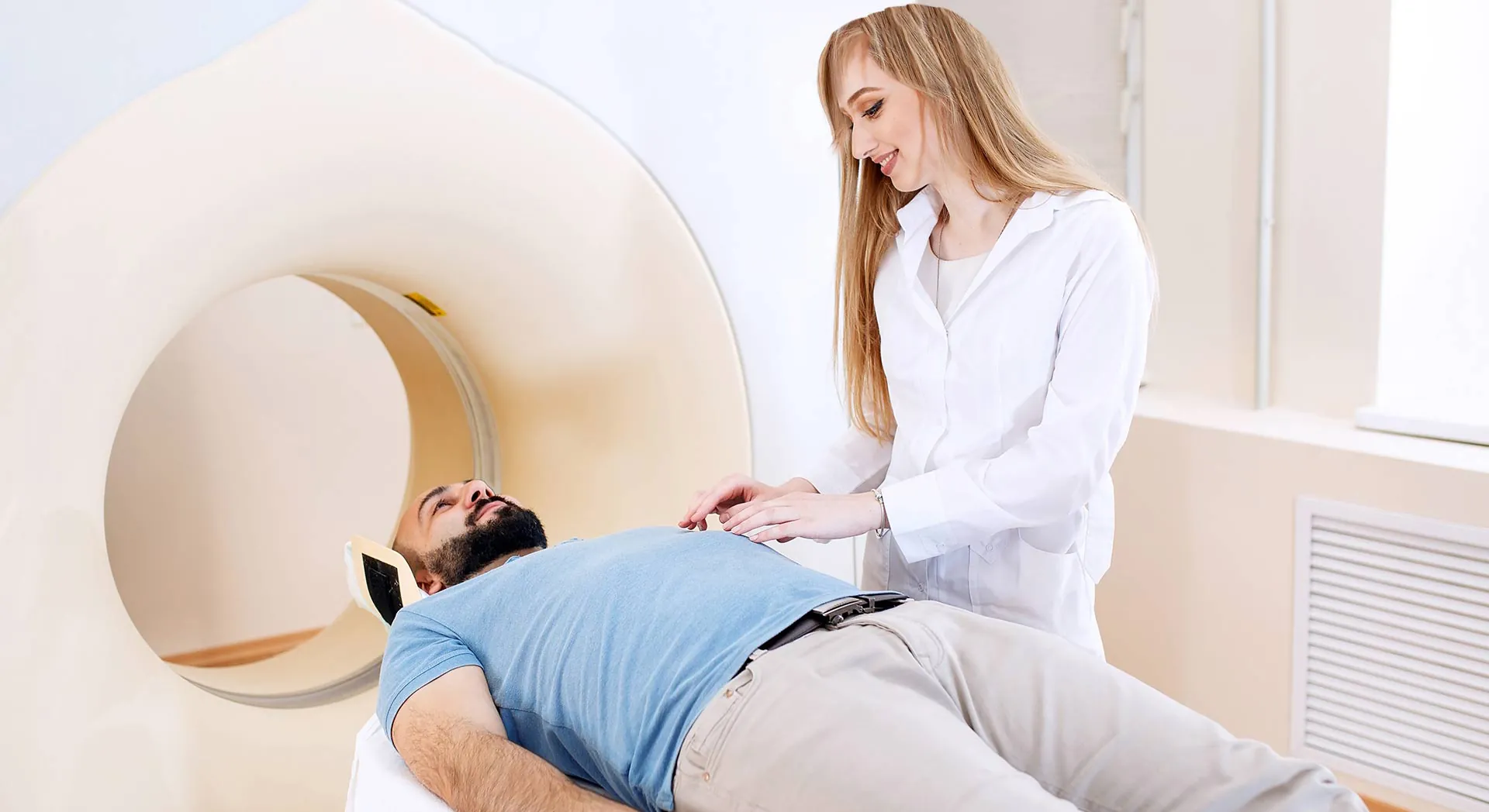 Radiology technologist with a patient at a CT scanner